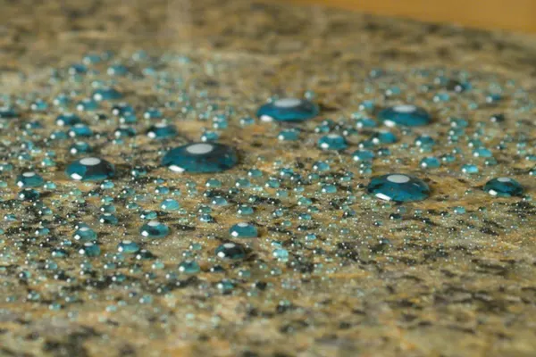 Treated granite with Diamond Bond, blue dye beading on the surface